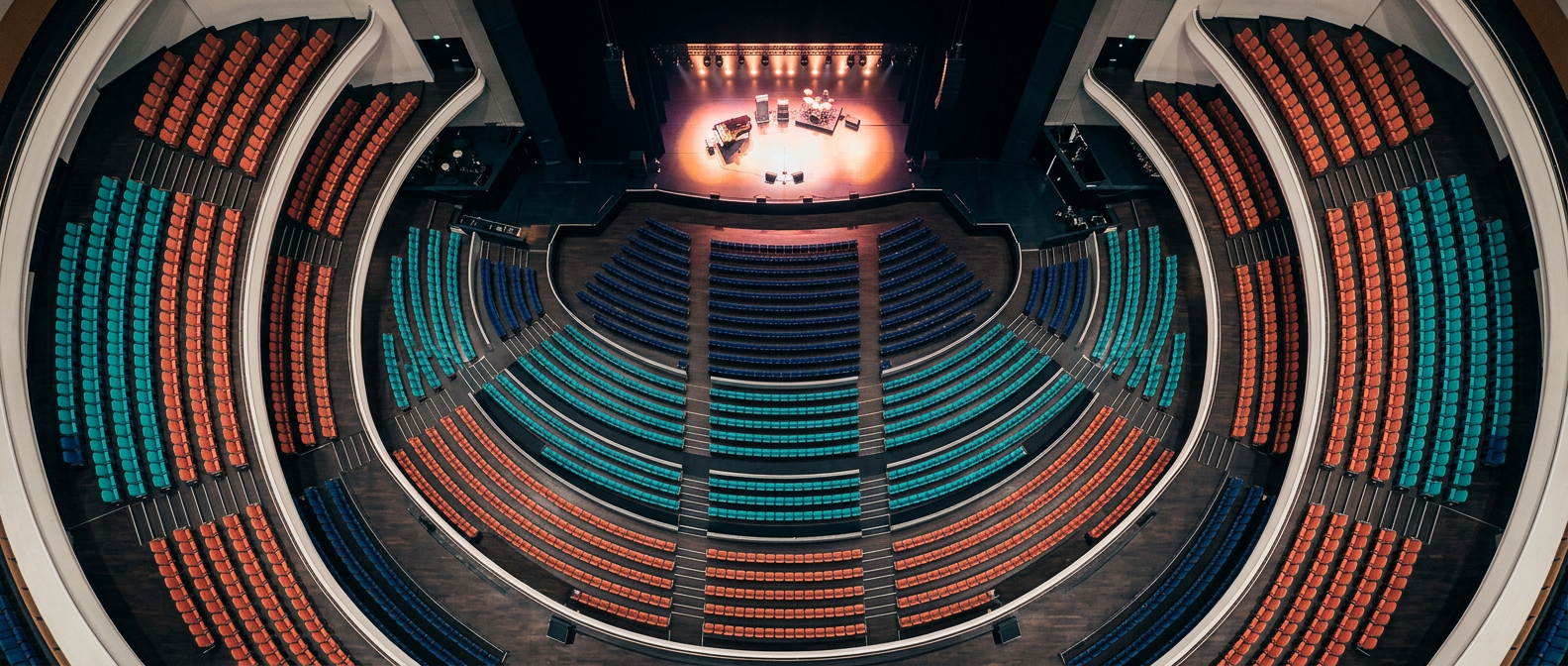 A concert hall seating plan seen from above, sections in teal, navy and coral